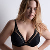 woman wearing a black bra against a plain background