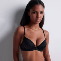 woman wearing a black bra against a plain background
