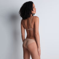 woman wearing a beige lingerie set against a plain background