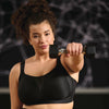 woman in black sports bra holding a dumbbell against a dark background