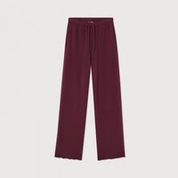 A pair of wide-leg lounge pants in a deep burgundy color, featuring an elastic waistband and a matching drawstring, displayed flat against a light off-white background.
