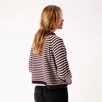 A woman modelling a dark brown and white horizontally striped knit sweater.