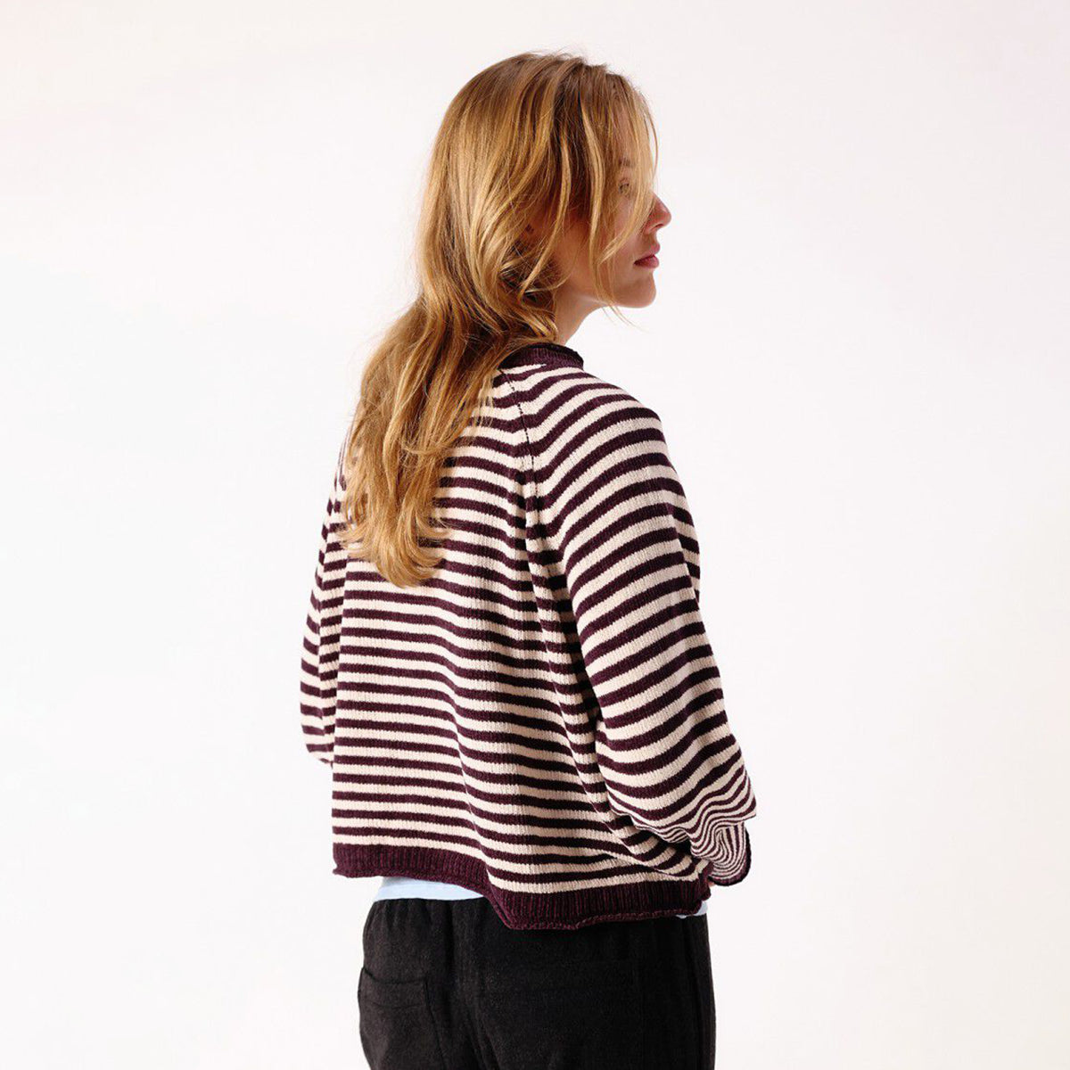 A woman modelling a dark brown and white horizontally striped knit sweater.
