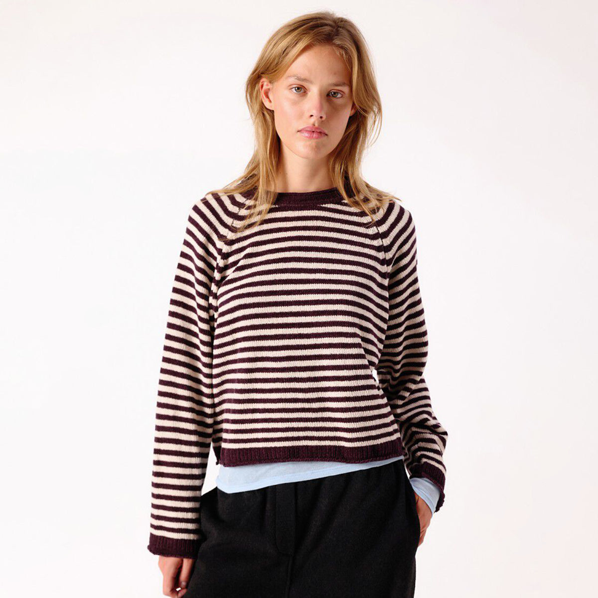 A woman modelling a dark brown and white horizontally striped knit sweater.