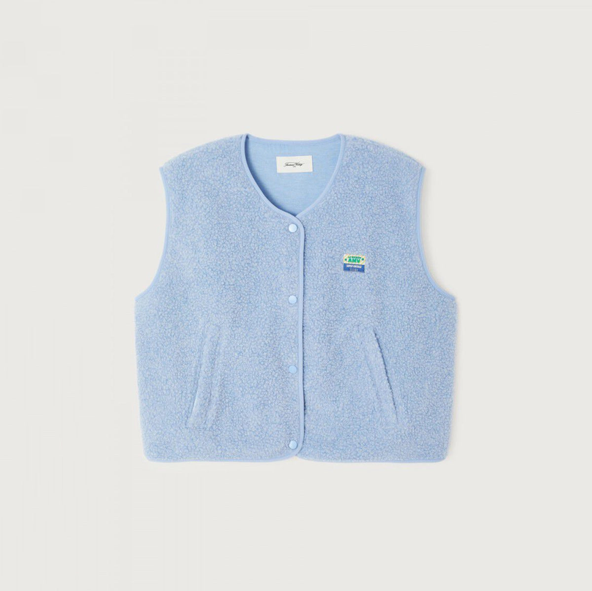 A light blue fuzzy knit cardigan vest with a button-up front, two front pockets, and a small logo patch on the left chest, displayed flat against a light beige background.