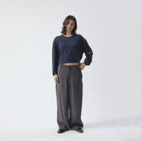 A woman modeling a dark navy blue long-sleeve top and dark gray wide-leg trousers against a plain white studio background.