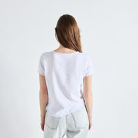 A woman viewed from behind wearing a plain white short-sleeve t-shirt and light-wash jeans against a clean white studio background.