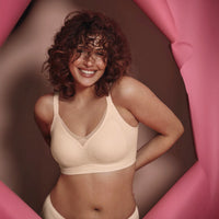 woman wearing a beige bra against a pink and brown background