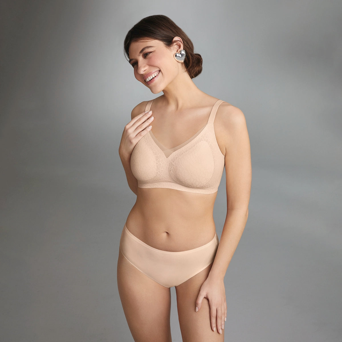 woman wearing a beige bra and panties set against a grey background