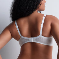 A woman shown from the back wearing a white underwire bra with a textured band and adjustable shoulder straps, photographed against a light gray studio background.