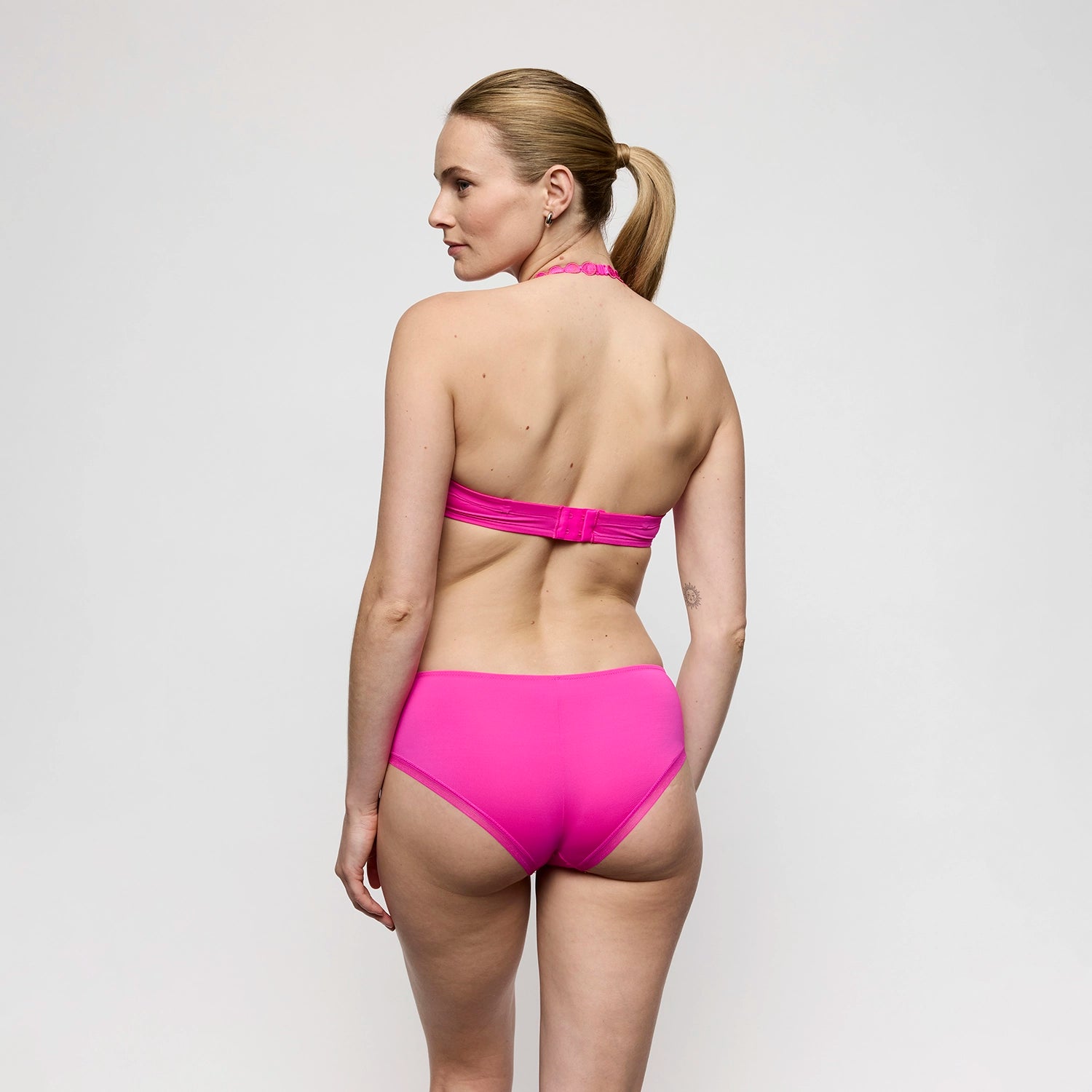 woman wearing a pink lingerie against a plain background