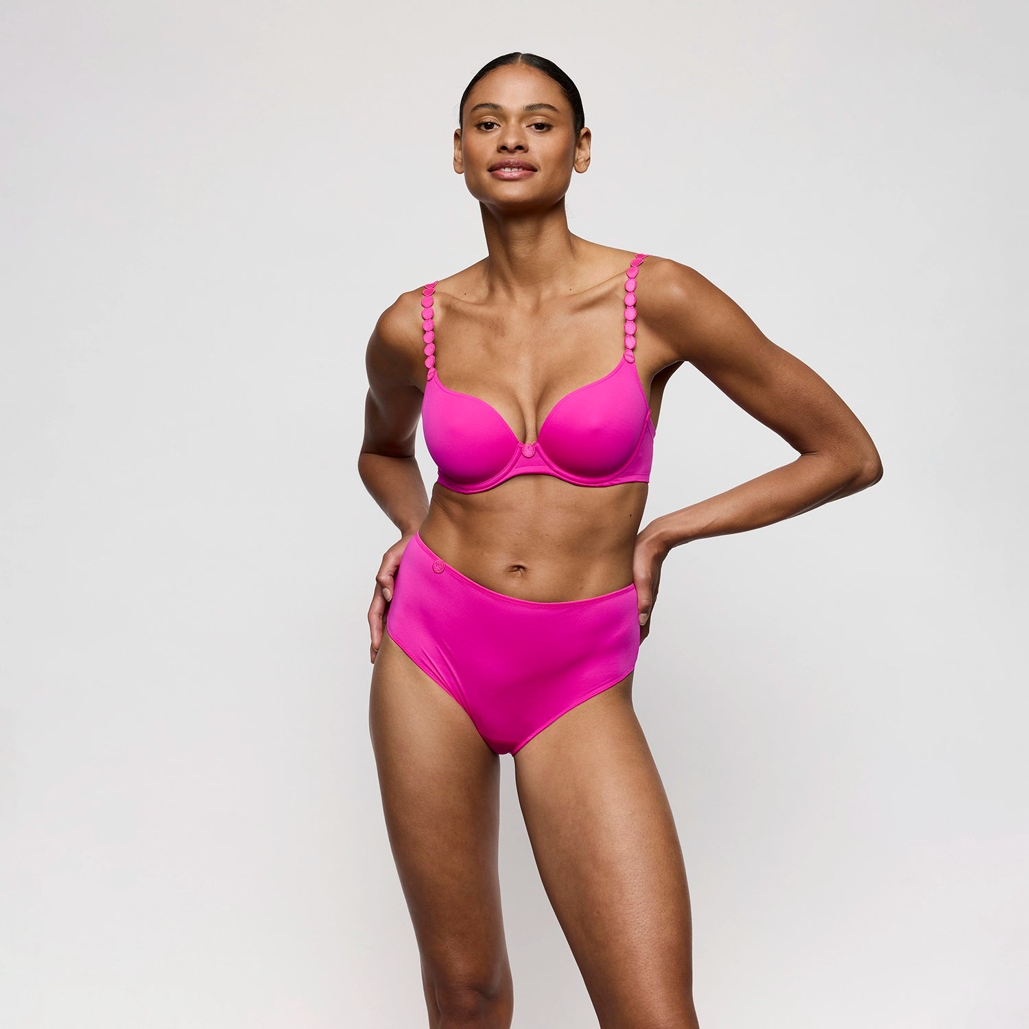 woman wearing a bright pink lingerie on a plain background
