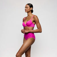 Woman wearing a bright pink lingerie against a plain background