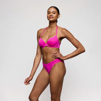 woman wearing a bright pink bikini against a plain background