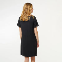 A woman with blonde hair is shown from the back wearing a black short-sleeve nightgown with lace trim on the sleeves, set against a plain white studio background.
