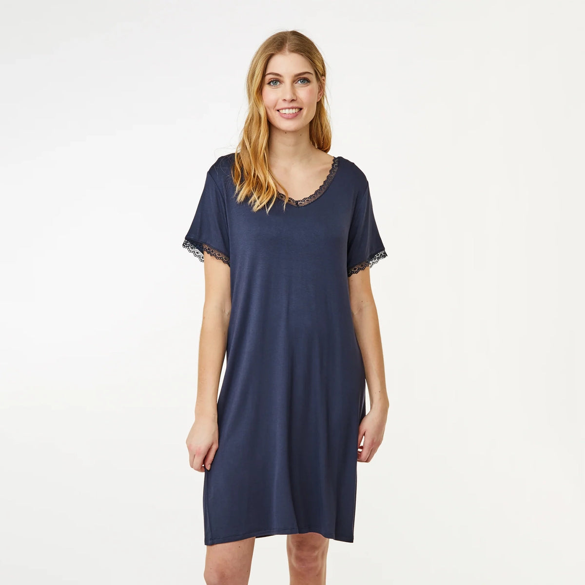 A woman modeling a navy blue short-sleeve nightgown with delicate lace trim along the scoop neckline and sleeve cuffs, set against a plain white studio background.