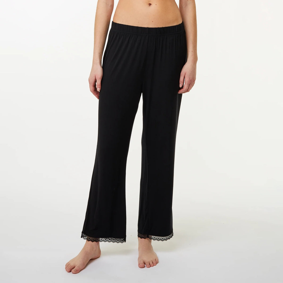 A model wearing black wide-leg lounge pants with a lace hem, shown from the waist down against a plain white studio background.