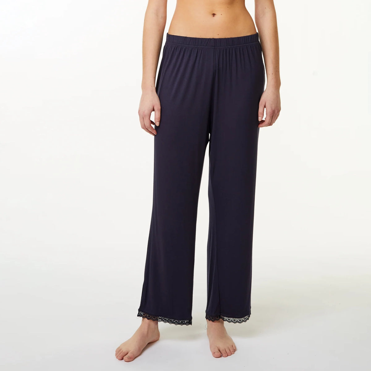 A model wearing dark navy blue wide-leg lounge pants with a lace hem, shown from the waist down against a plain white studio background.