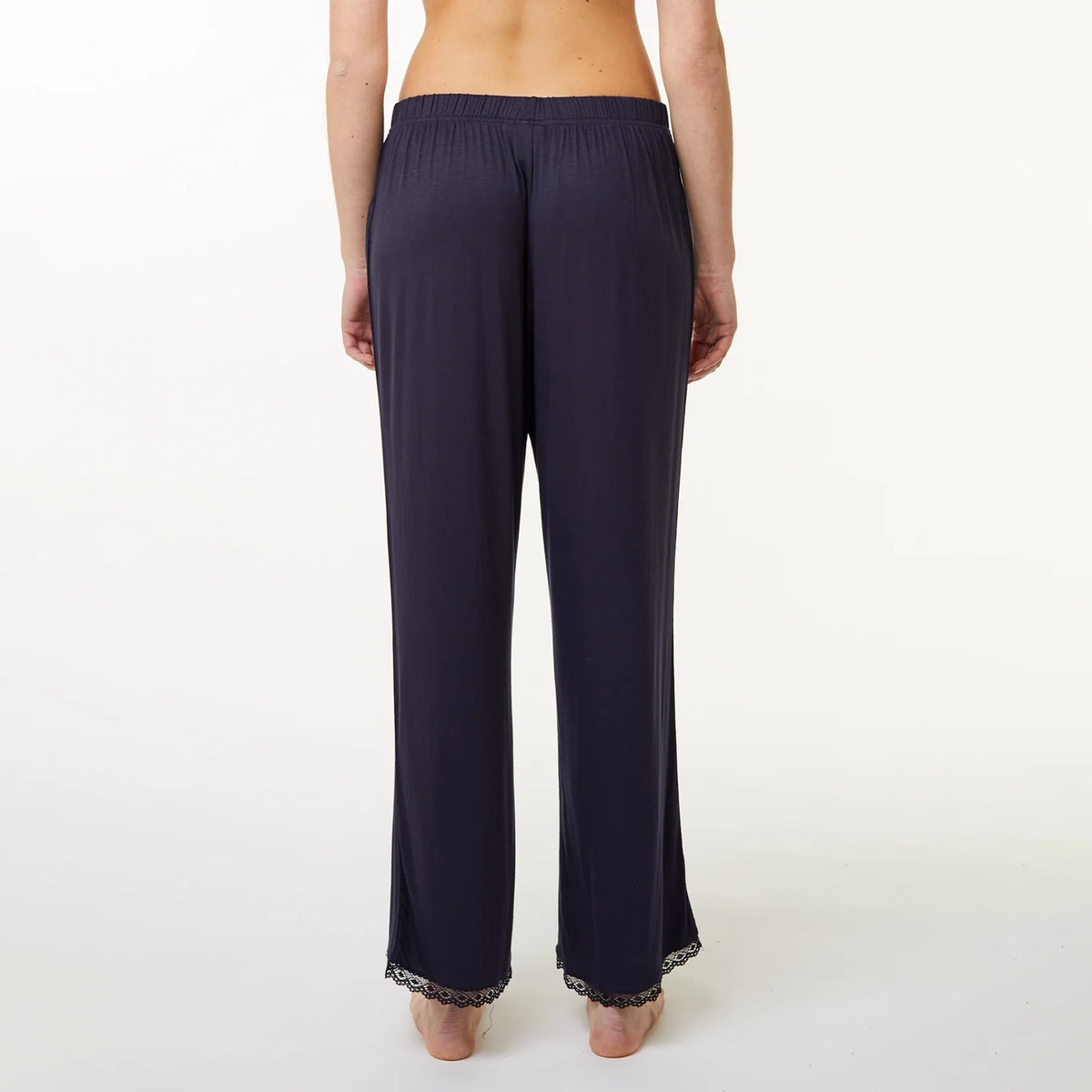 A model shown from the back wearing dark navy wide-leg lounge pants with a lace trim at the hem, against a plain white studio background.