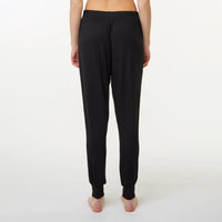 Black jogger-style pyjama pants shown from the back on a model, featuring an elastic waistband and ribbed ankle cuffs, against a plain white studio background.