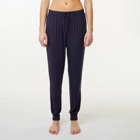 A model wearing dark blue jogger-style pyjama pants with a drawstring waist and elastic ankle cuffs, shown against a plain light gray studio background.
