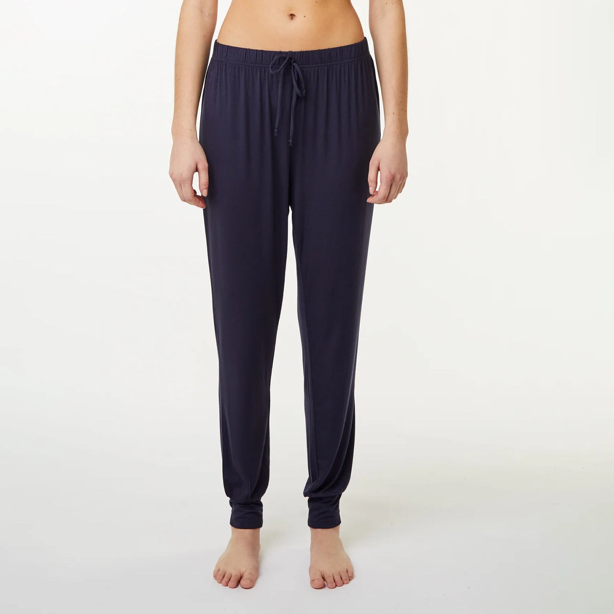 A model wearing dark blue jogger-style pyjama pants with a drawstring waist and elastic ankle cuffs, shown against a plain light gray studio background.