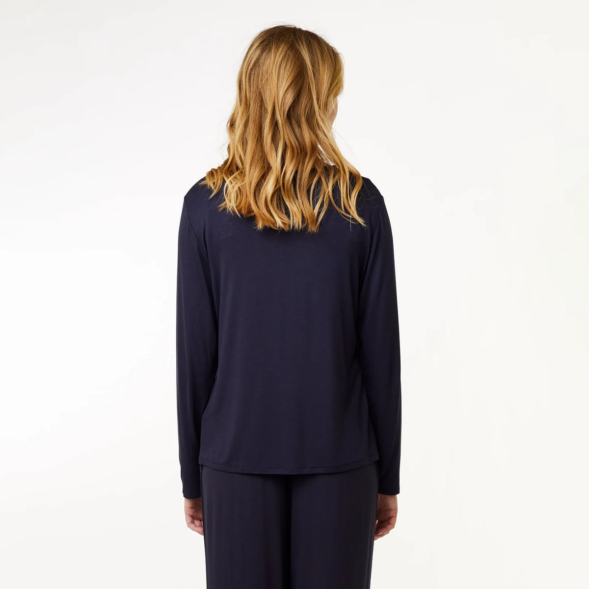 A woman with blonde hair is shown from the back wearing a dark navy blue long-sleeve top and matching pants against a plain white background.