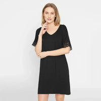A woman modeling a black short-sleeve V-neck nightdress with lace sleeve cuffs, photographed against a plain light gray studio background.
