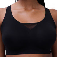 A close-up of a woman wearing a black wireless bralette with a scoop neckline and a subtle V-shaped mesh detail at the center front.