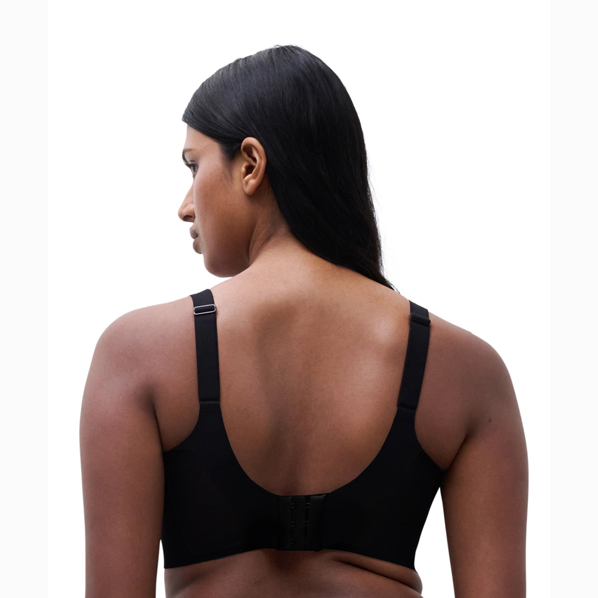 A woman shown from the back wearing a black bra, photographed against a plain white studio background.