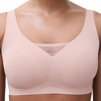 A close-up of a model wearing a light pink seamless wireless bra with a V-neckline and a subtle mesh band at the center.