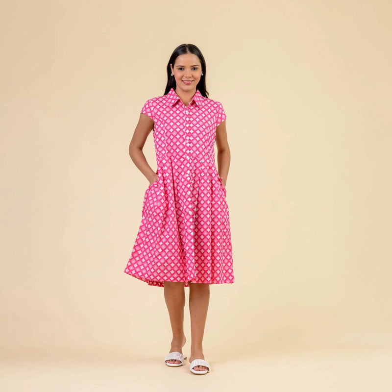 Woman wearing a pink dress with white  geo print on a beige background