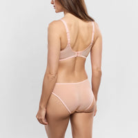 woman wearing a light pink lingerie set on a plain background