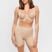 woman wearing a beige lace bra and matching shorts on a light grey background