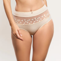 a close-up of a model wearing high-waisted sheer mesh panties in a light beige/cream color with a decorative white polka-dot and circle pattern along the waistband.