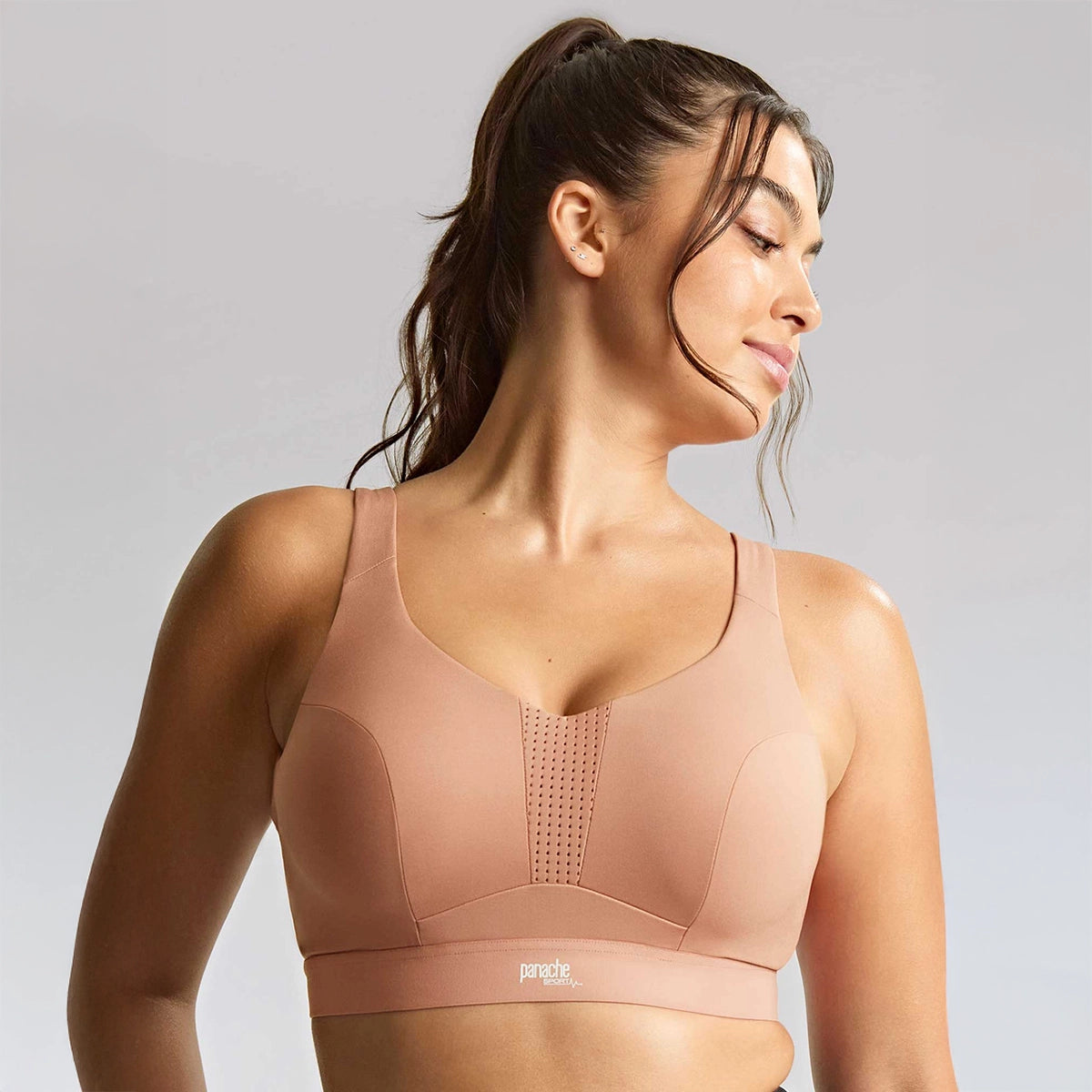 woman wearing a beige sports bra with a visible brand logo on a light grey background