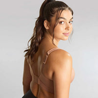 woman wearing a beige sports bra with a gray background