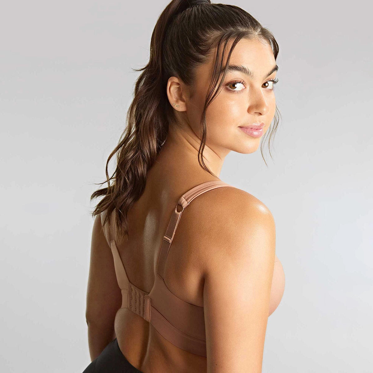 woman wearing a beige sports bra with a gray background