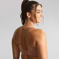 woman wearing a beige bralette against a plain background