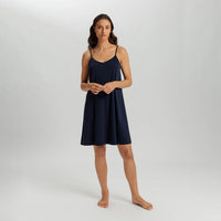 A woman modeling a navy blue slip-on camisole nightgown against a light gray studio background.