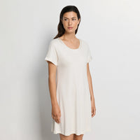 Woman wearing white nightdress against a plain background