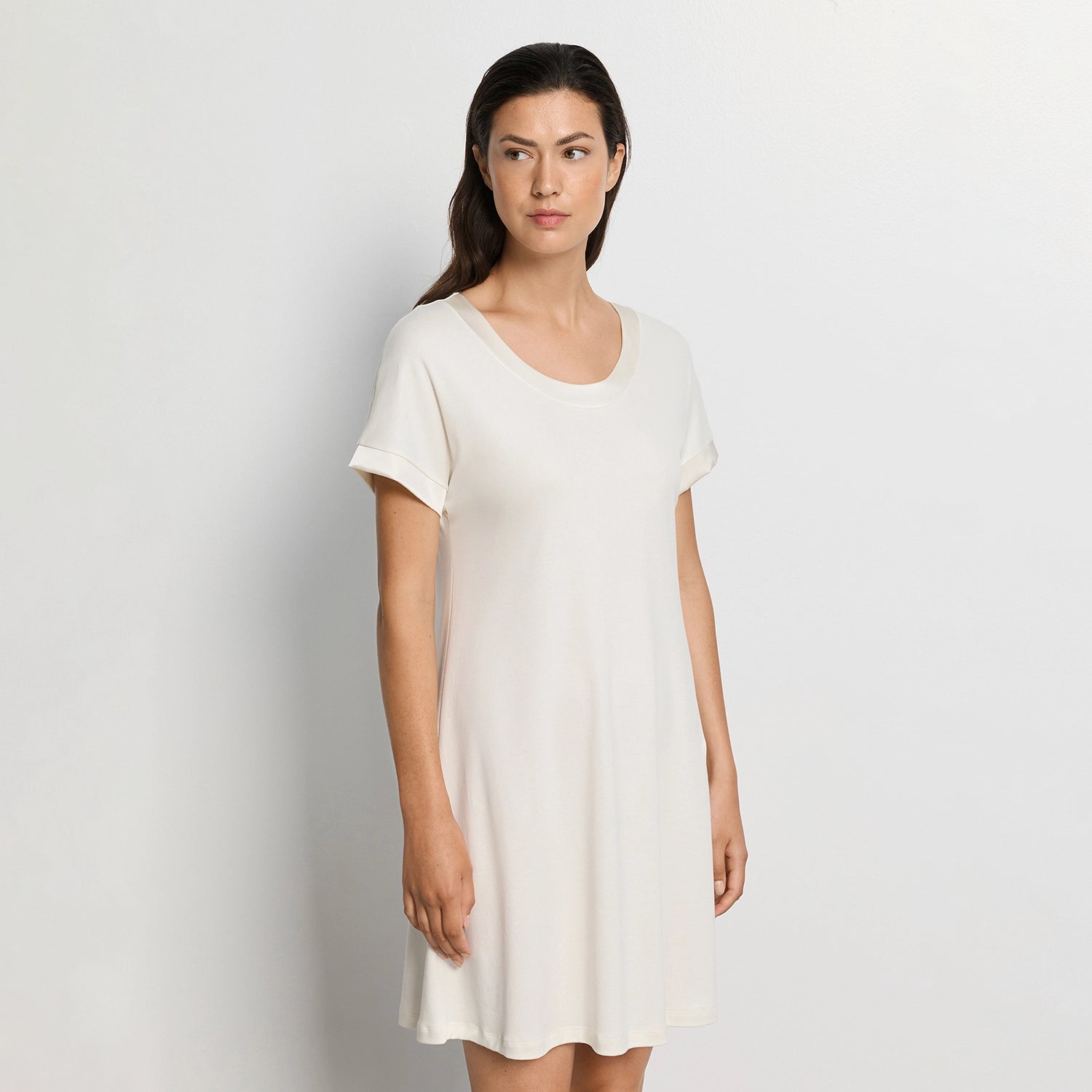 Woman wearing white nightdress against a plain background