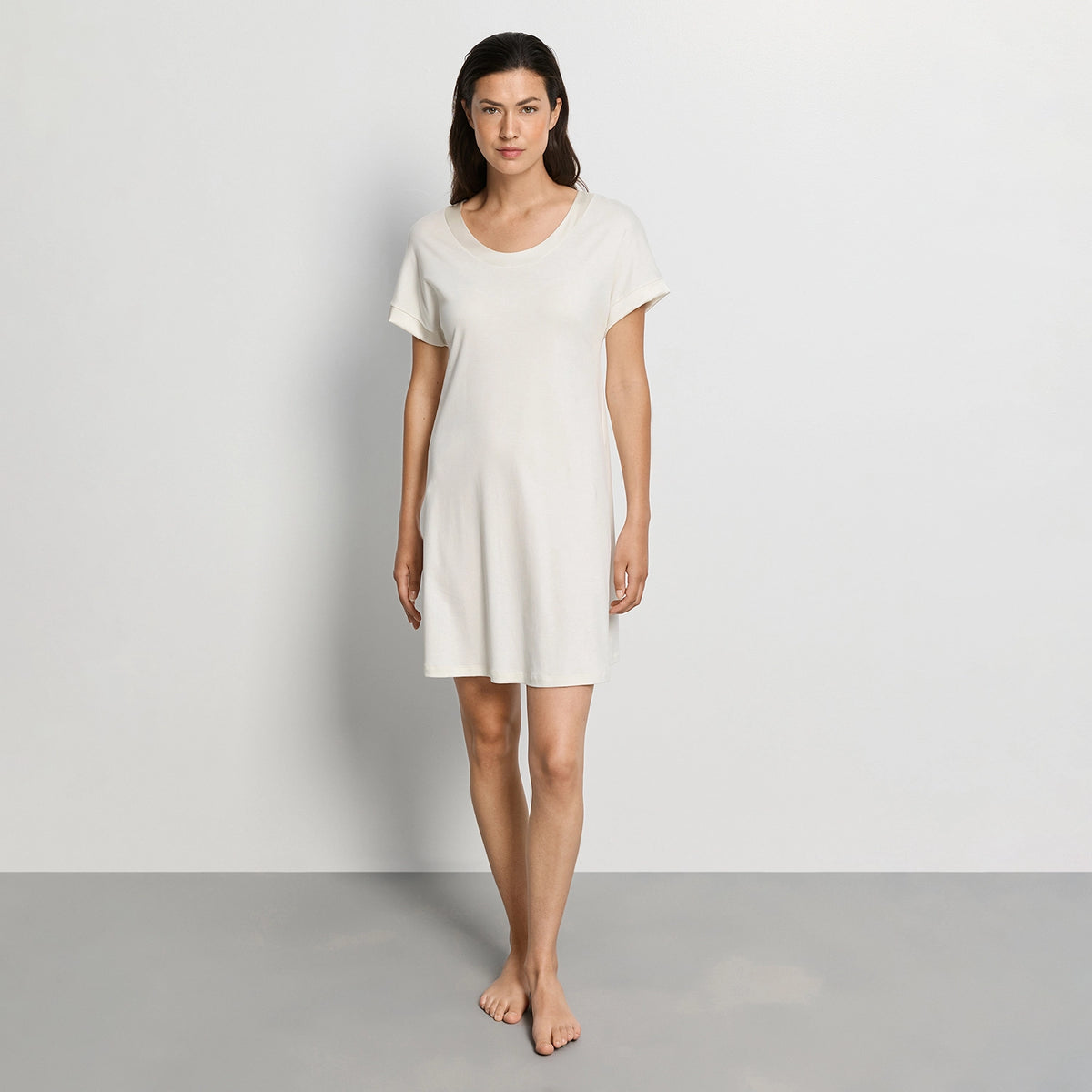 woman wearing a white nightdress against a plain background