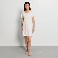 woman wearing a white nightdress against a plain background
