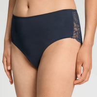 A close-up of a model wearing high-waisted navy blue underwear with a lace side panel, shown against a light gray studio background.