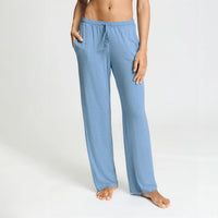 A person modeling light blue heather lounge pants with an elastic drawstring waistband and side pockets, shown against a plain light gray studio background.
