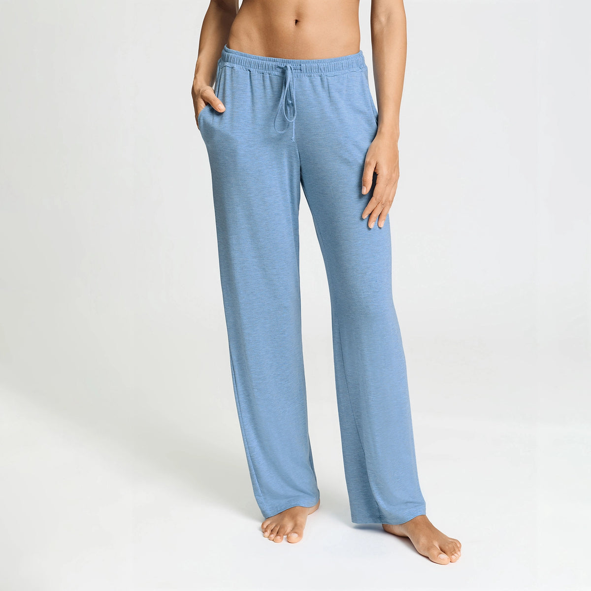A person modeling light blue heather lounge pants with an elastic drawstring waistband and side pockets, shown against a plain light gray studio background.