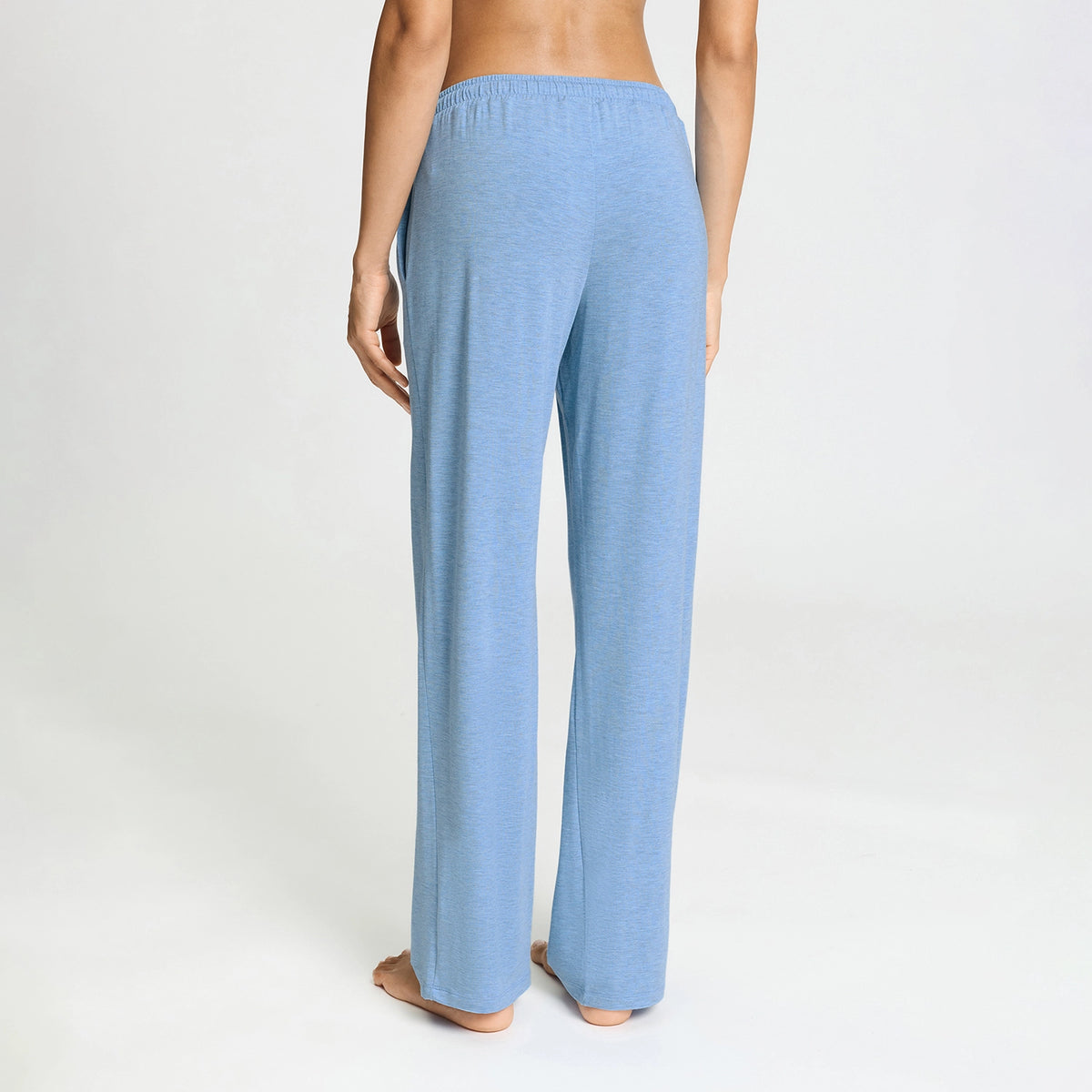 A person shown from the back wearing light blue heathered lounge pants against a plain light gray studio background.