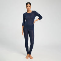 A woman modeling a matching navy blue two-piece knit loungewear set, featuring a long-sleeve top with lace trim at the neckline and cuffs, paired with matching full-length leggings, against a light gray studio background.