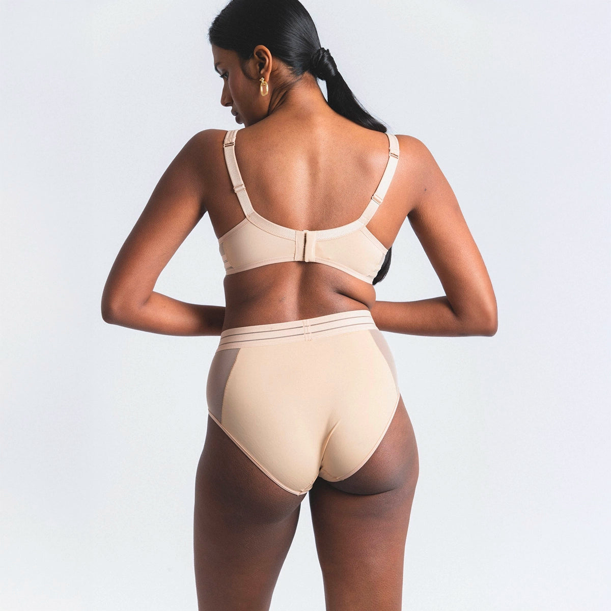 woman wearing a beige bra and panties set on a light grey background